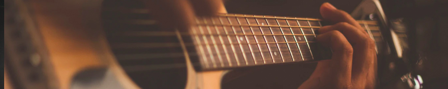 Close up of an acoustic guitar and a hand holding down a chord